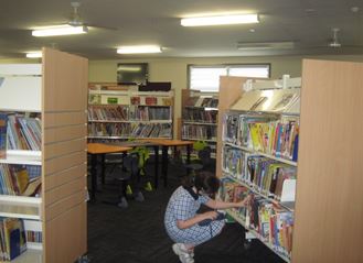 Student reaching for book inside library